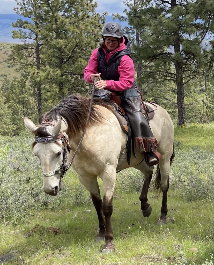 Susann riding a buckskin colored horse